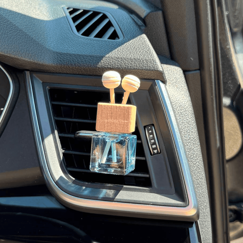 Air vent car diffuser with luxury fragrance bottle and wooden lid, stylish interior decor accessory.